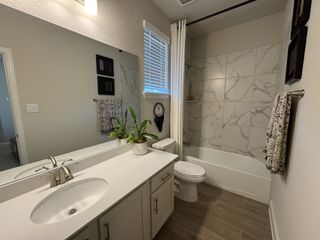 A modern bathroom featuring a marble-tiled shower, sleek vanity, and contemporary fixtures.