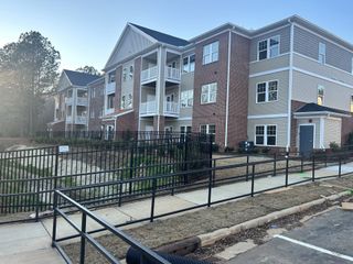 A modern multi-level apartment building with balconies and brick exterior in Weatherstone Creek by ExperienceOne Homes, LLC (Cary, NC).