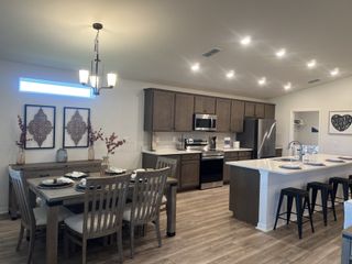 A modern kitchen-dining area with wood cabinetry, a large island, and elegant lighting.