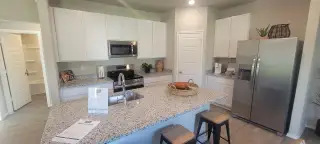 Model Home A modern kitchen with granite countertops, stainless steel appliances, and sleek white cabinetry.