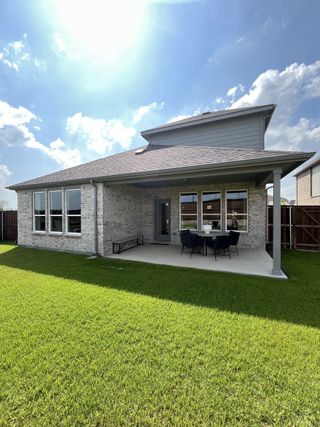 Model Home A charming brick home with a covered patio and lush yard in Wilson Creek Meadows by Pulte Homes (Celina, TX).