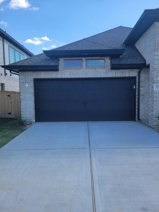 A modern brick home with a sleek black garage in Fulbrook on Fulshear Creek 60' by Perry Homes (Fulshear, TX).