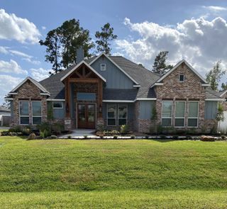 A charming brick and wood home with a manicured lawn in Mostyn Manor Reserve by Harrisburg Homes (Magnolia, TX).