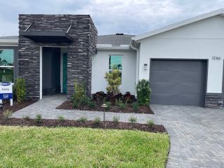 A modern home with sleek stone accents and a manicured yard in Tradition - Kenley by Mattamy Homes (Port St. Lucie, FL).