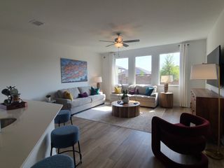Model Home A bright living room with cozy sofas, colorful cushions, modern art, and abundant natural light from large windows.
