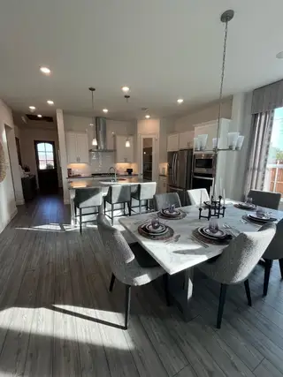 A modern kitchen with elegant marble dining table, cozy gray chairs, and sleek lighting fixtures.