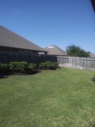 Model Home A lush green backyard with a privacy fence and neatly trimmed bushes, perfect for outdoor relaxation and activities.