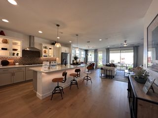 Spacious open-concept kitchen with a modern island, wood floors, and inviting living space leading to outdoor views.