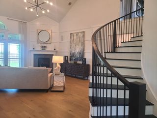 Model Home A modern living room with a curved staircase, chic lighting, and elegant decor.