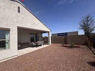A cozy backyard patio with seating and a gravel landscape in Monroe Ranch by K. Hovnanian® Homes (Buckeye, AZ).
