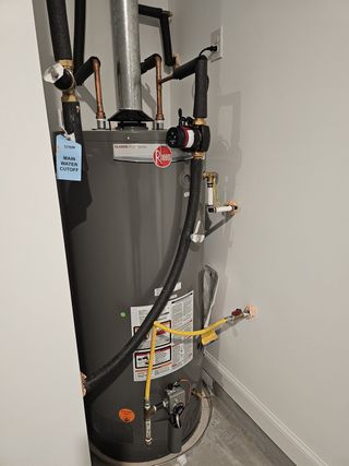 A modern water heater unit in a utility room with labeled water cutoff, efficient piping, and venting.
