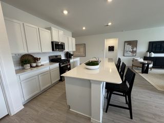 A modern kitchen with sleek white cabinets, a spacious island, and elegant decor, seamlessly connected to an open living area.