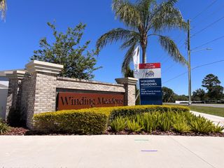 The elegant entrance to Winding Meadows by Pulte Homes (Apopka, FL), featuring lush landscaping and a beautifully crafted brick sign.