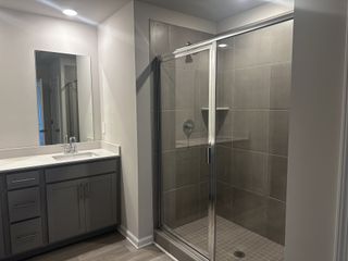 A modern bathroom with a sleek glass shower, gray vanity, and minimalist design elements.
