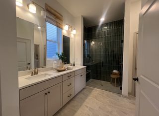 Model Home Elegant bathroom with a dual-sink vanity, modern lighting, and a sleek black-tiled shower.