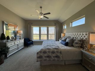 A cozy bedroom featuring a tufted bed, plush carpet, large windows, and elegant decor.