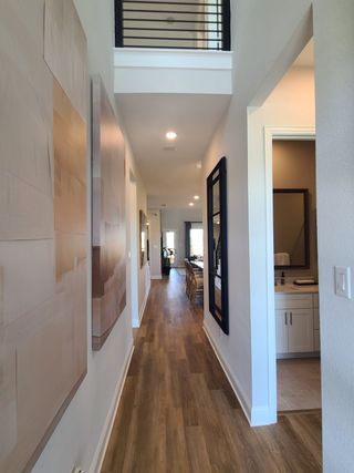 Model Home A bright hallway with sleek wood flooring, modern art, and a view into a cozy dining area.