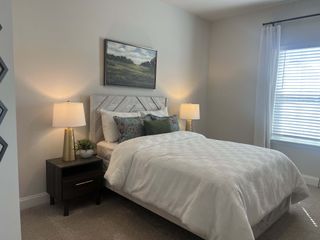 A cozy bedroom with a textured headboard, elegant lamps, and soft lighting, creating a relaxing, stylish atmosphere.