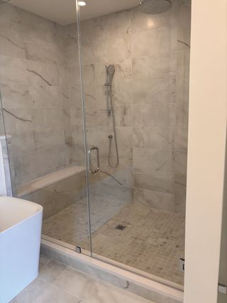 A modern bathroom featuring a sleek glass shower with marble tiles and a luxurious soaking tub.
