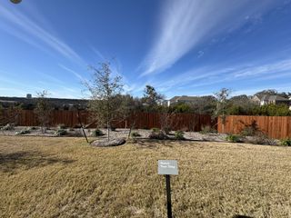 Model Home A serene backyard with lush lawn and wooden fence in River Bluff by KB Home (Leander, TX).