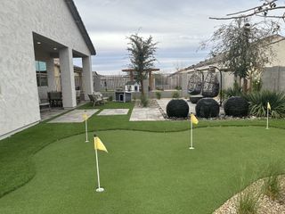 Street view A beautiful backyard with a putting green, seating area, and landscaping in Pinnacle at San Tan Heights by Mattamy Homes (San Tan Valley, AZ).