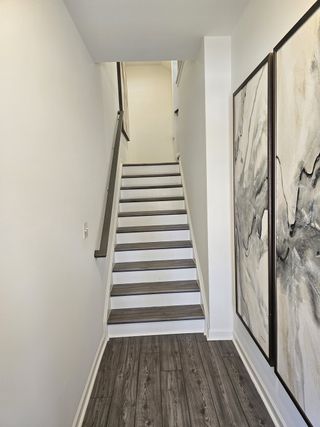 Model Home A modern staircase with wood flooring and abstract wall art, creating a sleek and minimalistic look.