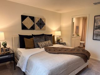 A cozy bedroom featuring elegant decor, plush bedding, and soft lighting, offering a welcoming ambiance with an ensuite bathroom.