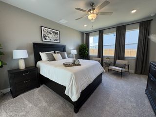 A cozy bedroom featuring a dark wood bed frame, soft carpeting, and ample natural light through large windows.