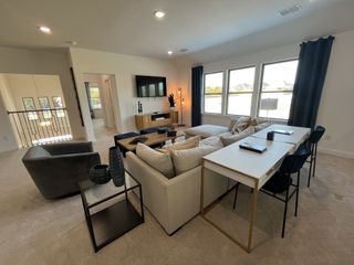 A spacious living room with a cozy sectional, modern decor, and large windows for ample natural light.