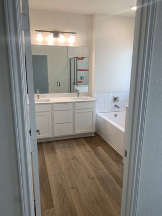 Model Home A bright primary bathroom featuring dual sinks, a soaking tub, and elegant lighting.