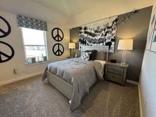 A cozy bedroom featuring peace sign decor, a gray bed set, and stylish lamps, creating a peaceful and modern atmosphere.