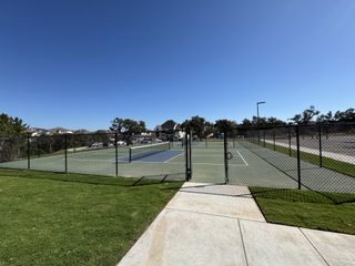 A community tennis court under a clear sky in Parkside on the River by M/I Homes (Georgetown, TX).