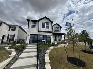 A striking modern home with stone accents and landscaped pathway in Highcrest Meadow West by Tri Pointe Homes (Georgetown, TX).