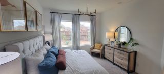 A serene bedroom with a tufted headboard, elegant lighting, and large windows that bring in natural light.