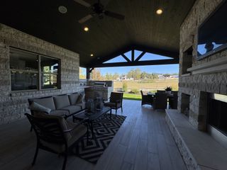 A spacious patio with cozy seating, fireplace, and grill, offering scenic views. Perfect for outdoor entertaining and relaxation.