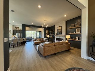 A modern living room with a cozy fireplace, chic chandelier, leather sofas, and open layout to the dining area.