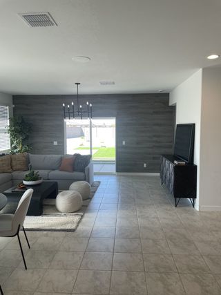 Model Home A contemporary living room with a sleek sofa, cozy poufs, and elegant tile flooring, complemented by a stylish TV console.