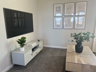 A contemporary living room with a wall-mounted TV, minimalist cabinet, framed art, and elegant decor accents.