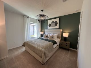 Model Home A cozy bedroom with an accent wall, plush carpeting, and elegant décor, creating a serene retreat.