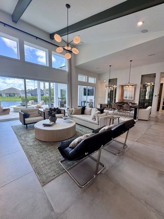 A modern open living area with high ceilings, large windows, chic light fixtures, and elegant furnishings.