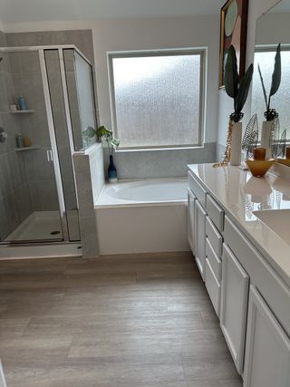 A modern bathroom featuring a glass shower, spacious tub, and sleek white vanity with decorative accents.