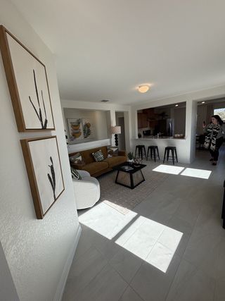A bright living area with modern art, cozy seating, and a kitchen bar, filled with natural light.