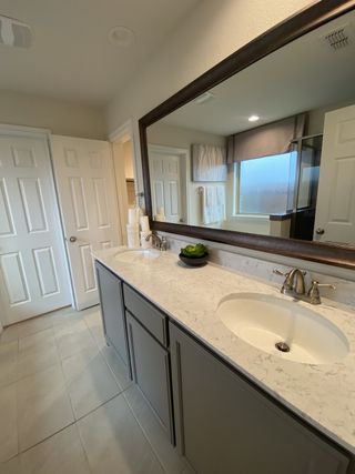 A sleek bathroom with a spacious mirror, dual sinks, and elegant gray cabinetry, offering a modern and functional design.