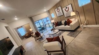 A sophisticated living room with neutral furnishings, bold accent pillows, and large windows opening to an outdoor patio.