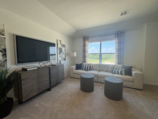 A modern living room with a large TV, comfortable sofa, stylish decor, and a scenic view through a wide window.