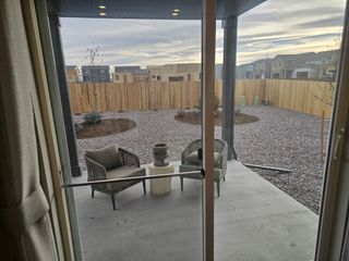 A cozy patio with modern seating overlooks a landscaped backyard with stone accents and wooden fencing.