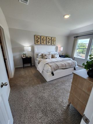 A serene bedroom with a plush white bed, elegant lighting, and a soft neutral color palette.