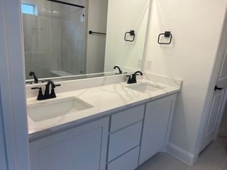 Model Home A modern bathroom with dual sinks, sleek black fixtures, and a spacious walk-in shower.
