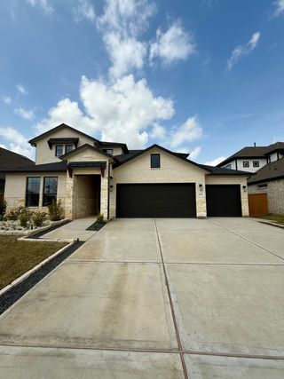 Street view A modern two-story home with a spacious driveway and sleek facade in Sunterra by CastleRock Communities (Katy, TX).