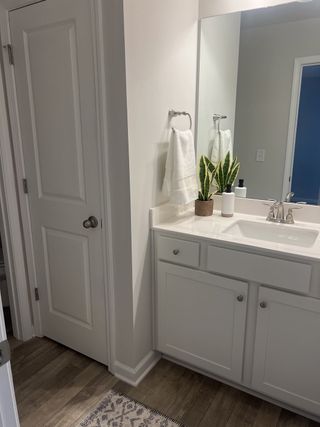A sleek bathroom featuring a white vanity, modern fixtures, and a chic potted plant accent.